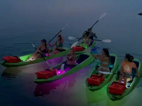 A group of kayakers exploring St. Andrews Bay on kayaks fitted with colorful LED lights - one of the top outdoor activities in Panama City Beach.