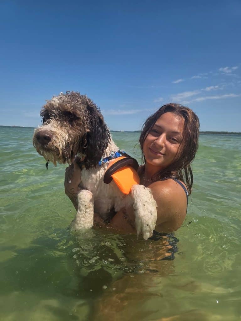Girl holding her dog in the water at Shell Island during a boat tour with Flippin’ Awesome Adventures, one of the top dog friendly things to do in Panama City Beach.
