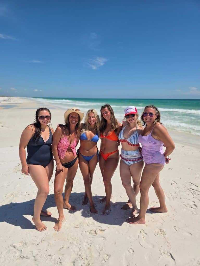 Women posing on the white sand beaches of Shell Island during a private boat tour in Panama City Beach, Florida.