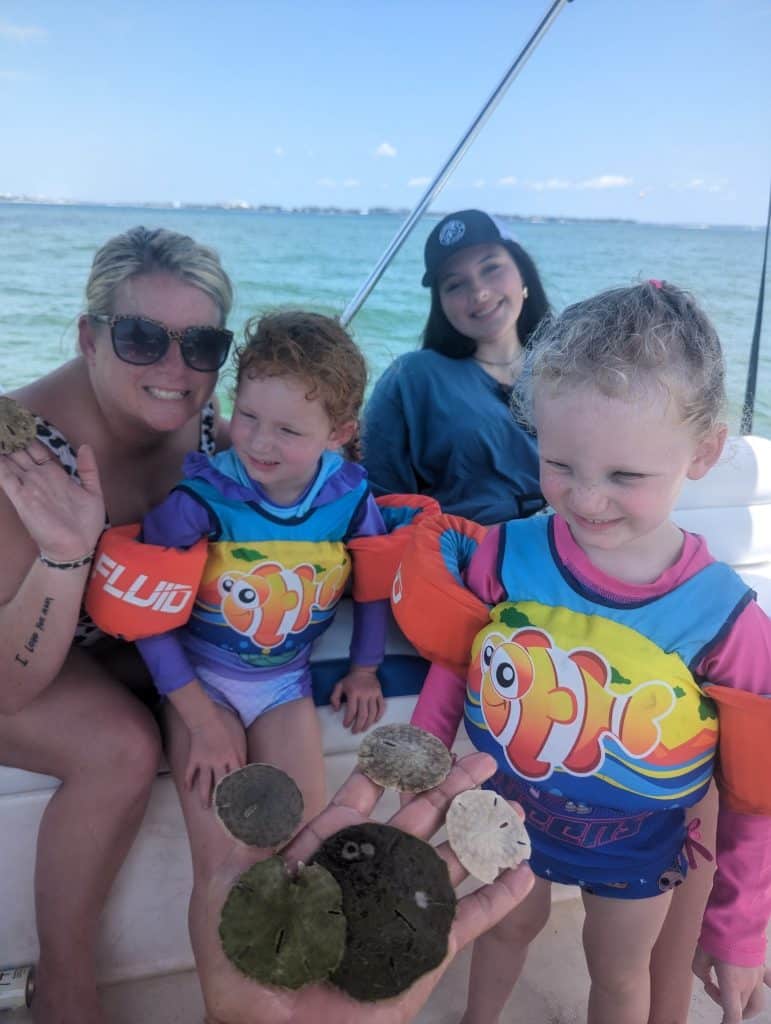 Family discovering live sand dollars during a marine biologist dolphin tour in Panama City Beach.