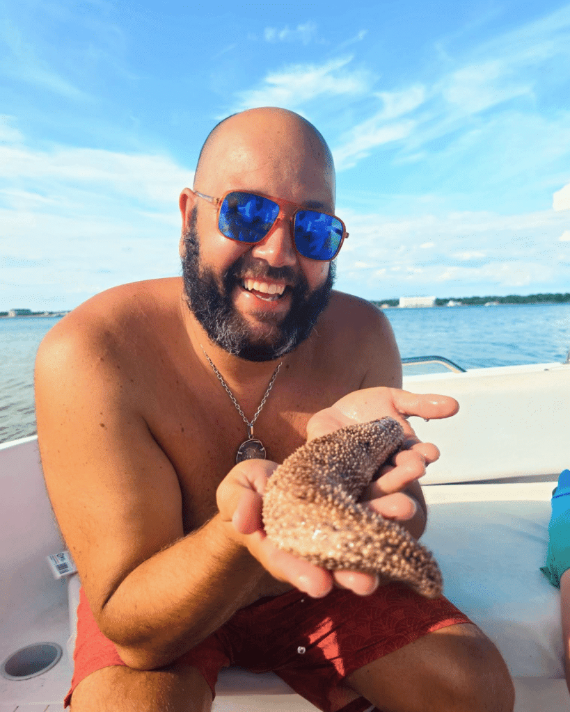 A guest holding a large sea cucumber in Panama City Beach on a Flippin' Awesome Adventures boat in St. Andrews Bay Florida