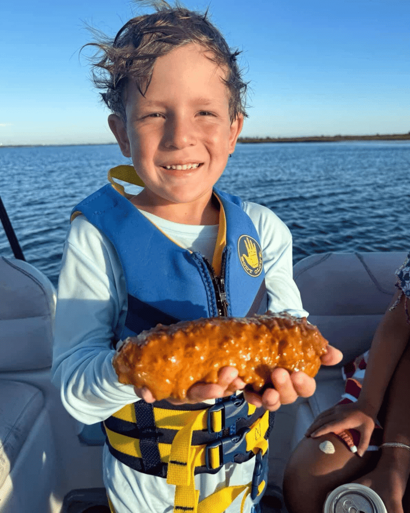 A young boy holding a princeps sea cucumber found during a Flippin' Awesome Adventures excursion on St. Andrews Bay, Panama City Beach