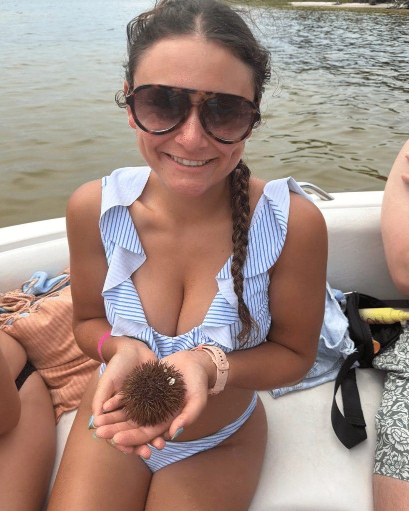 Guest holding a small brown variegated sea urchin found during a Panama City Beach dolphin and Shell Island excursion
